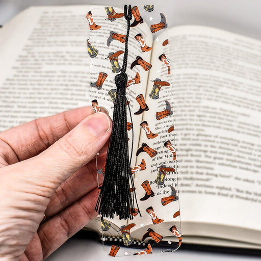 a hand holding a bookmark with a book in the background