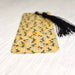 a yellow bookmark with a black tassel on top of it