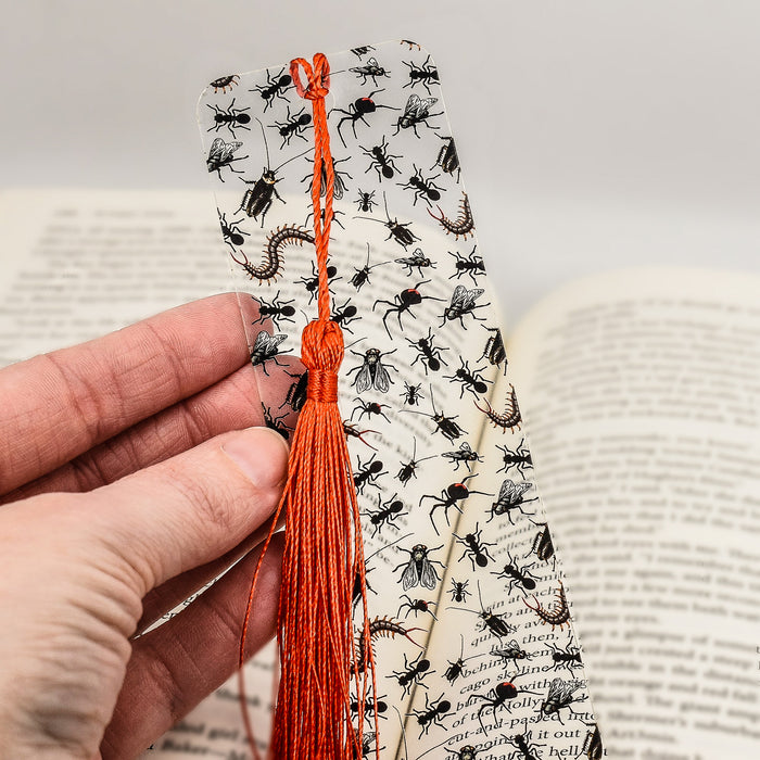 a person is holding a bookmark with flies on it