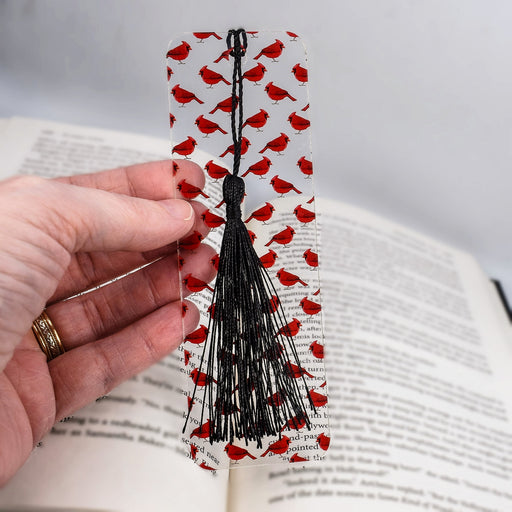 a hand holding a bookmark with red hearts on it