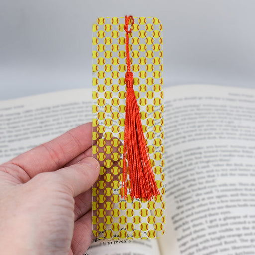 a hand holding a bookmark with a red tassel