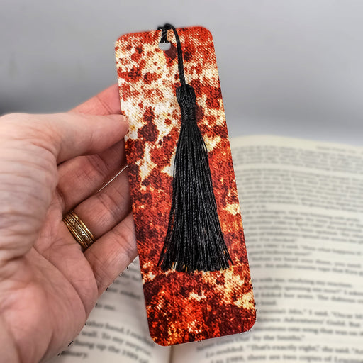 a hand holding a bookmark with a tassel