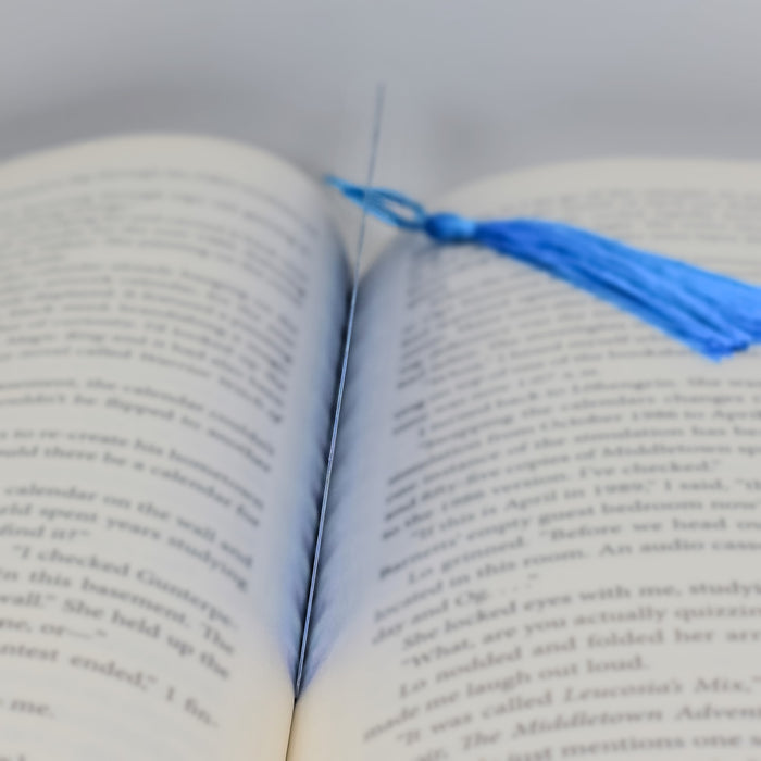 an open book with a blue tassel on top of it