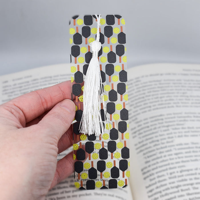 a person is holding a bookmark with a tassel