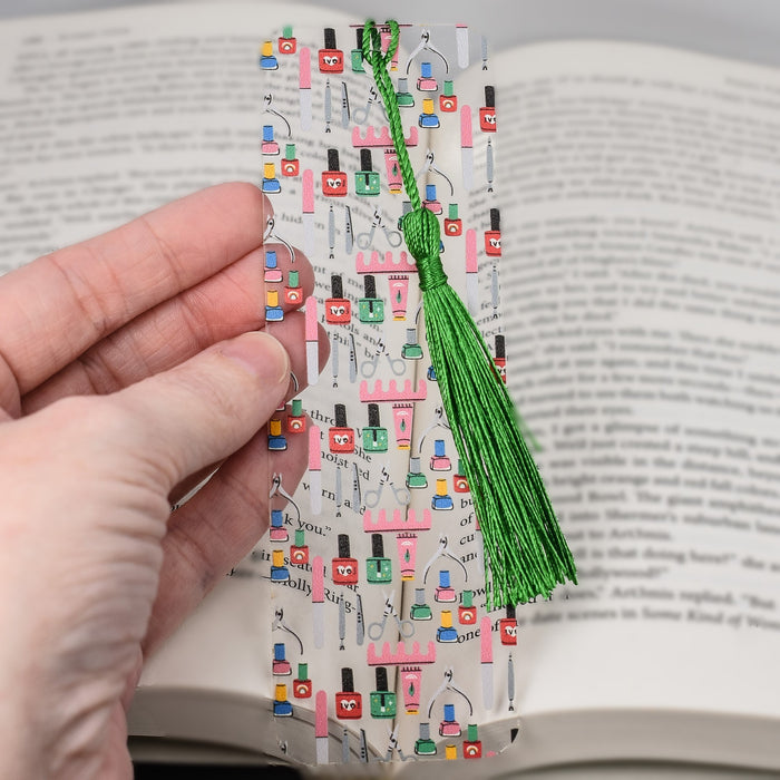 a hand holding a bookmark with a green tassel