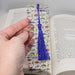 a person is holding a bookmark with a tassel