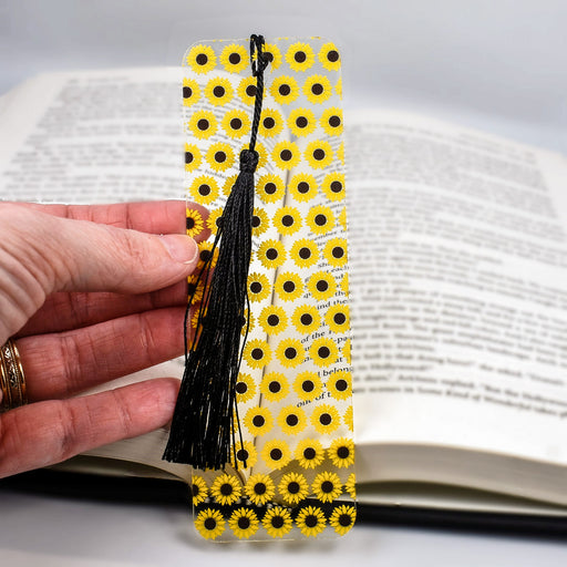 a hand holding a bookmark made out of yellow and black flowers