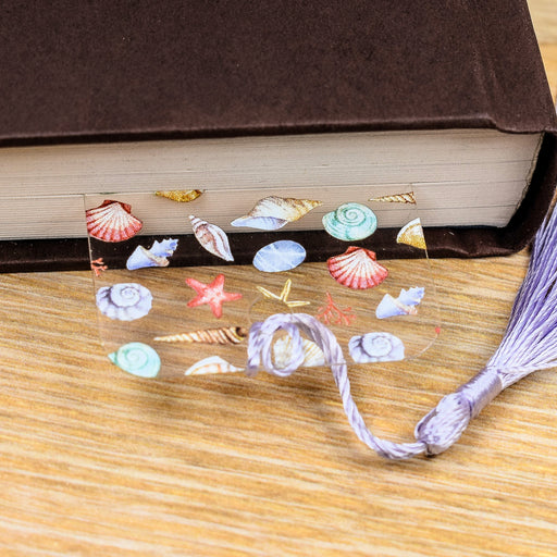 a book with sea shells and a tassel on top of it