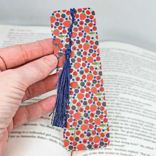 a person is holding a bookmark with a tassel