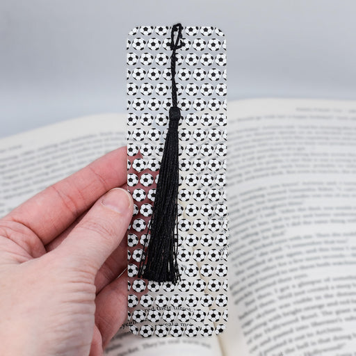 a hand holding a bookmark with a black tassel