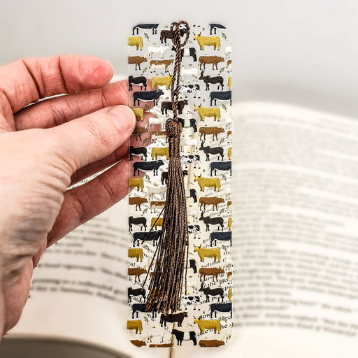 a person holding a bookmark with a book in the background