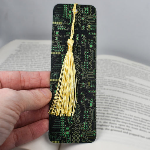 a hand holding a bookmark with a yellow tassel