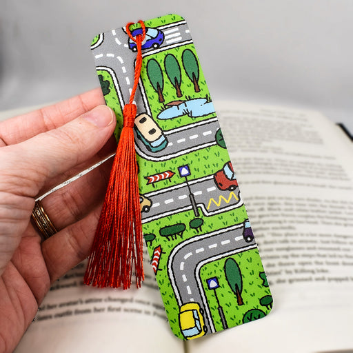 a hand holding a bookmark with a road and cars on it