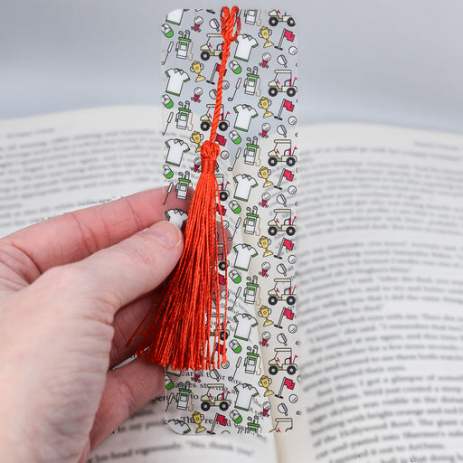 a person is holding a bookmark with a red tassel