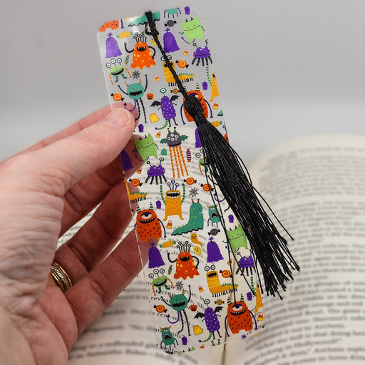 a hand holding a bookmark with a book in the background