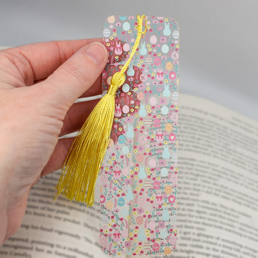 a hand holding a bookmark with a yellow tassel