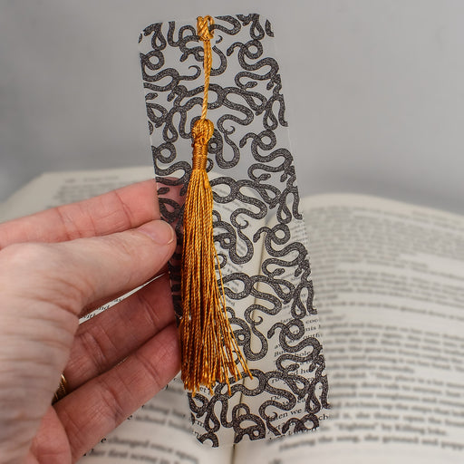 a person is holding a bookmark with a tassel