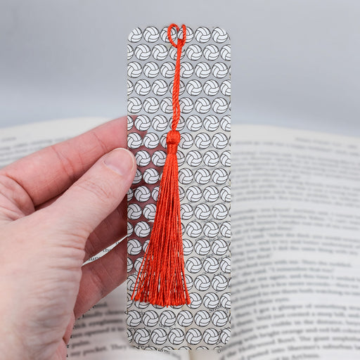 a hand holding a bookmark with a red tassel