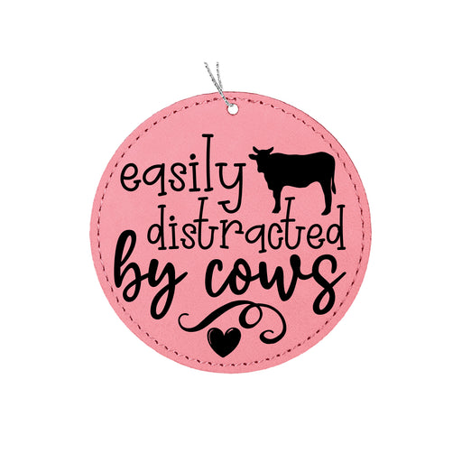 a pink round ornament with a cow saying easily distracted by cows