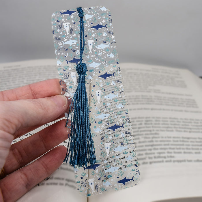 a hand holding a bookmark with a tassel on it