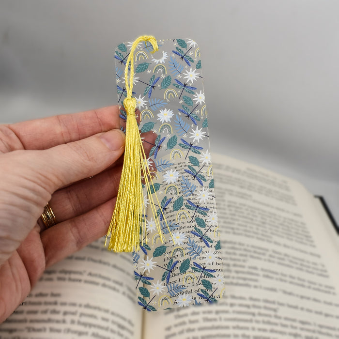 a person holding a bookmark with a book in the background