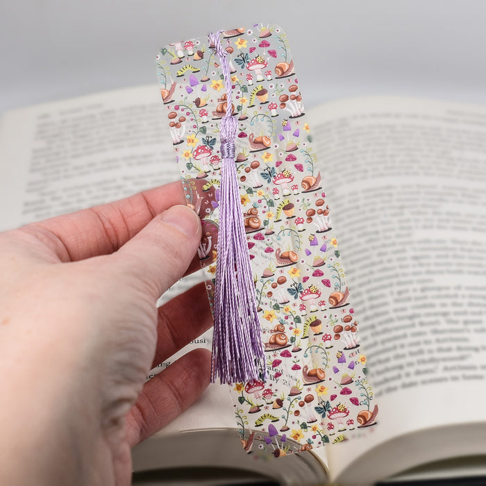 a hand holding a bookmark with a book in the background