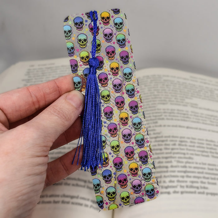 a hand holding a bookmark with skulls on it