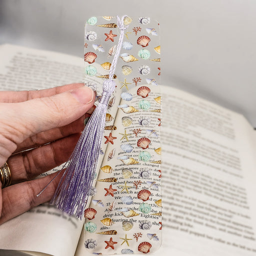 a person holding a bookmark with seashells on it