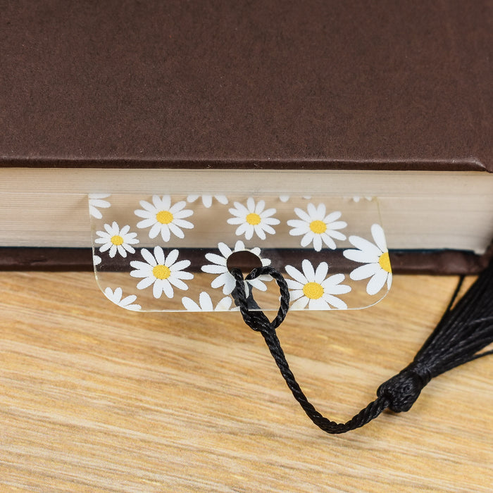 a book with a black tassel and white daisies on it