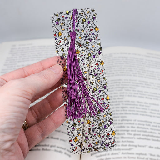 a hand holding a bookmark with a purple tassel
