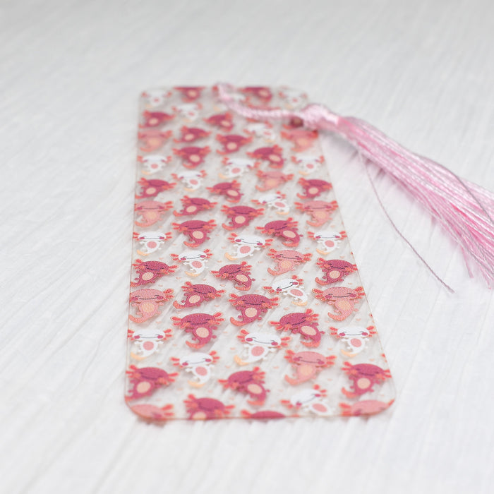 a pink and white bookmark with a pink tassel