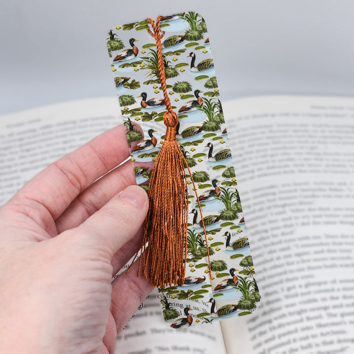 a hand holding a bookmark with a book in the background