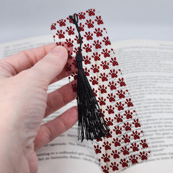 a person is holding a bookmark with a dog paw pattern on it