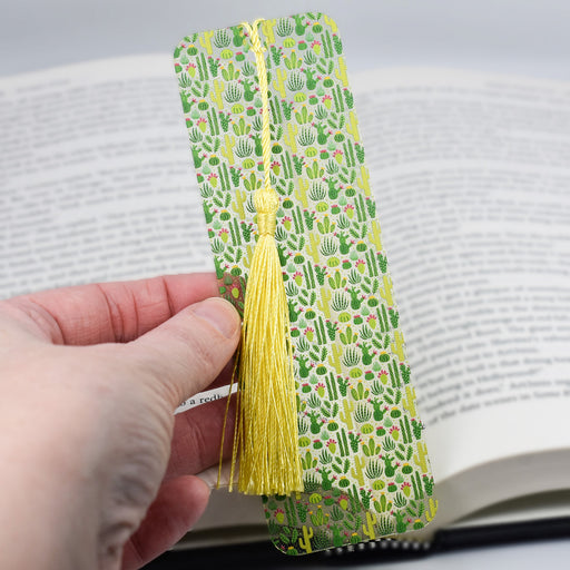 a person is holding a bookmark with a tassel