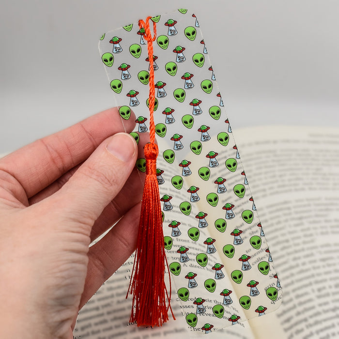 a person is holding a bookmark with a tassel