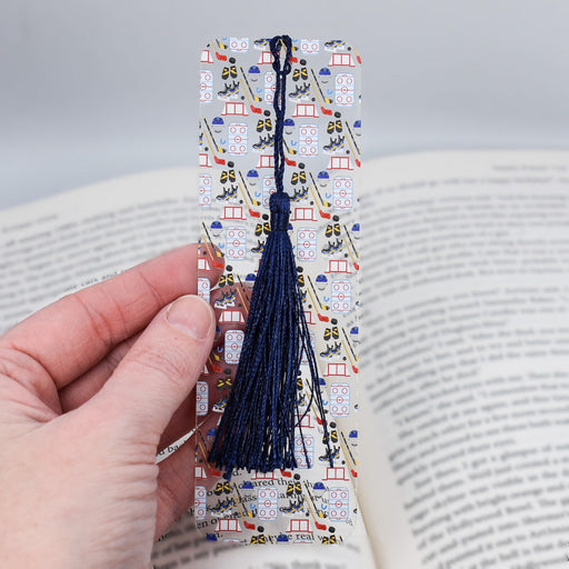 a person holding a bookmark with a tassel on it