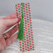 a person is holding a bookmark with a green tassel