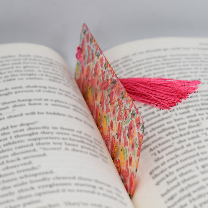 an open book with a pink tassel on top of it