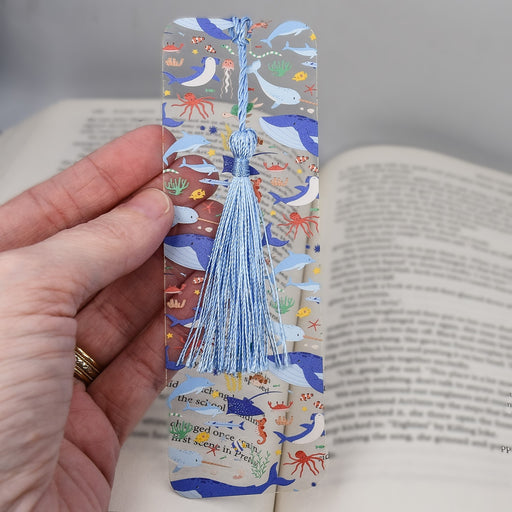 a hand holding a bookmark with a blue tassel