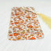 an orange and white patterned bookmark with a tassel