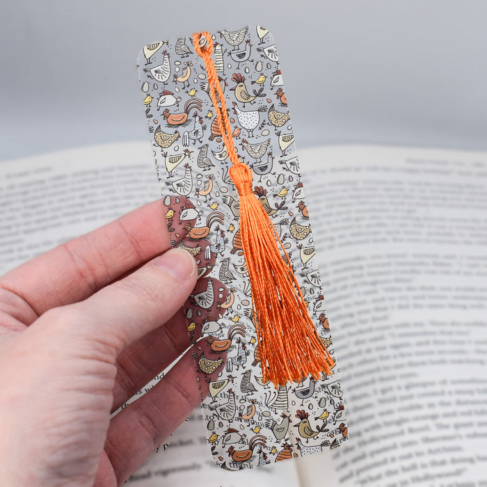 a hand holding a bookmark with an orange tassel