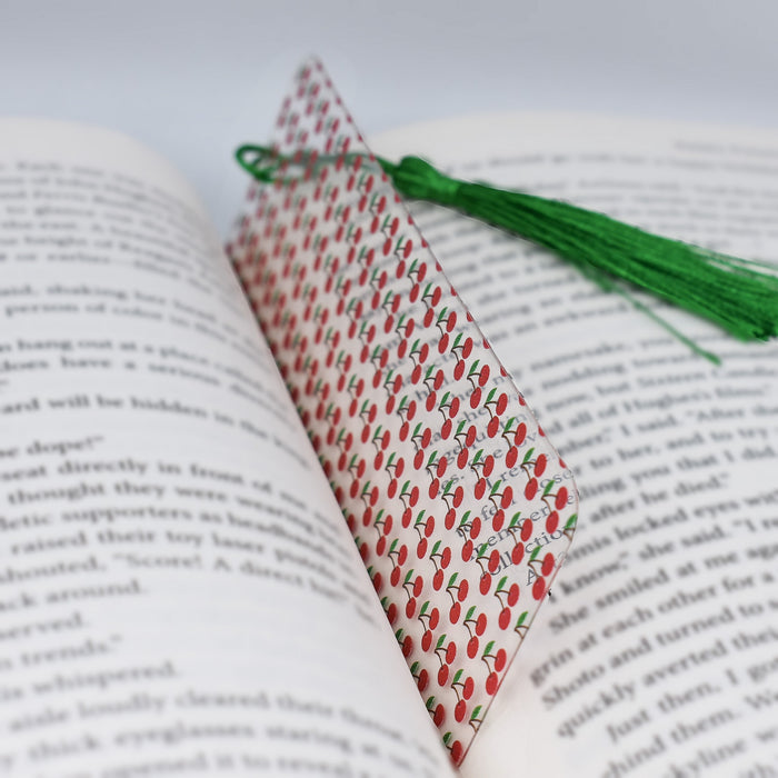 an open book with a green tassel on top of it