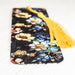 a tasseled bookmark with a floral design and a yellow tassel