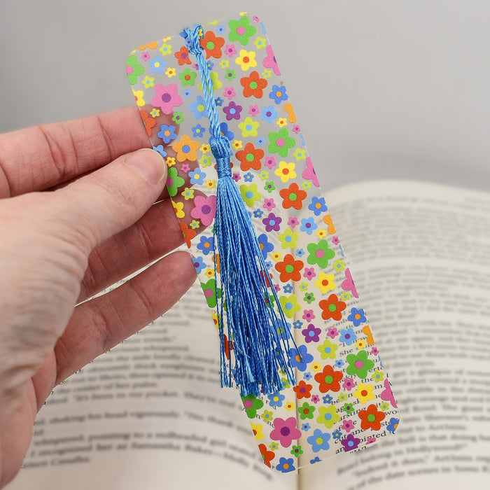 a hand holding a bookmark with a book in the background