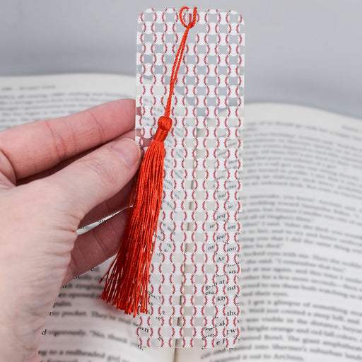 a hand holding a bookmark with a red tassel