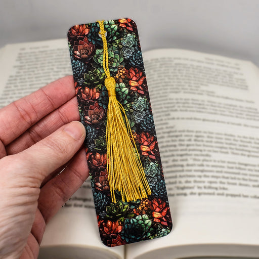 a hand holding a bookmark with a tassel on it