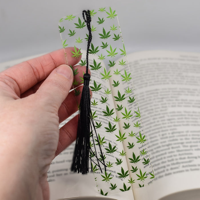 a person is holding a bookmark with marijuana leaves on it