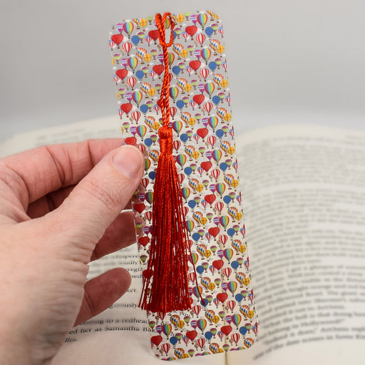 a hand holding a bookmark with a red tassel