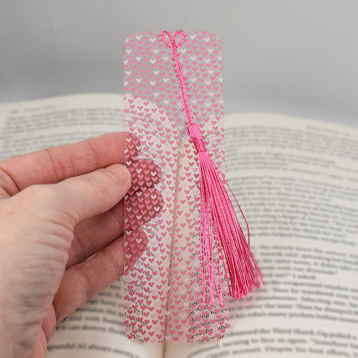 a person holding a bookmark with hearts on it