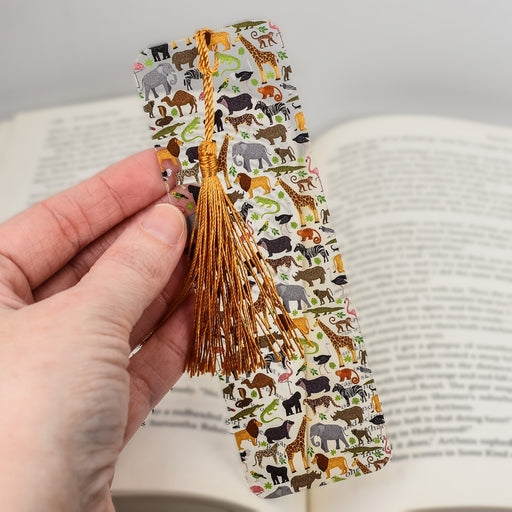 a hand holding a bookmark with animals on it